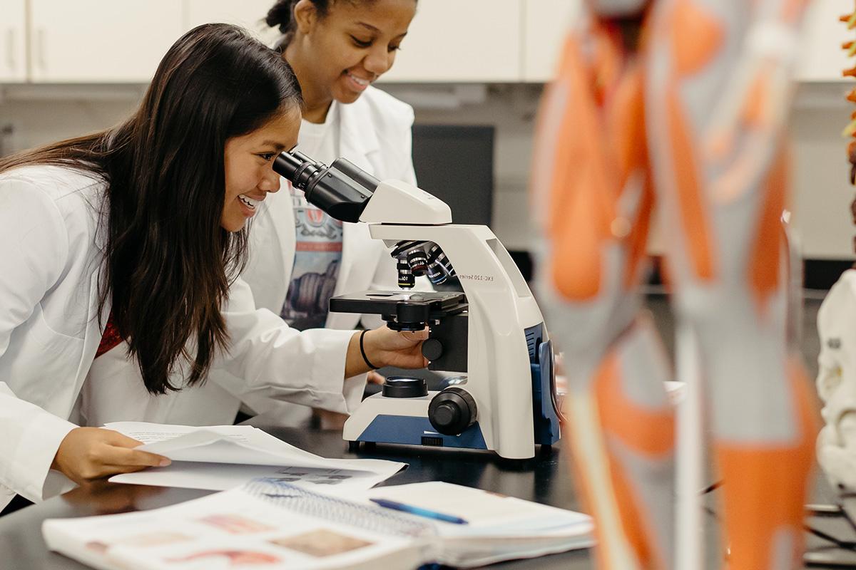 Student looks into a microscope in a laboratory session.