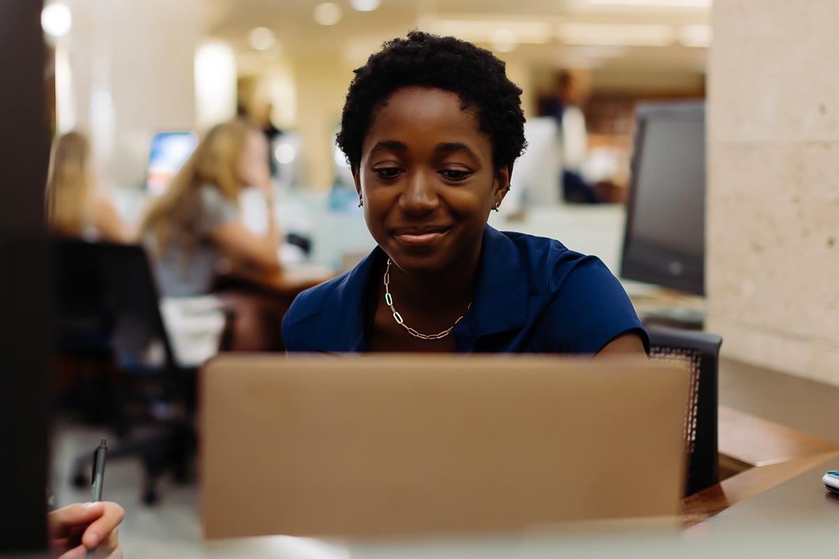 A PBA student works on a laptop in the library.